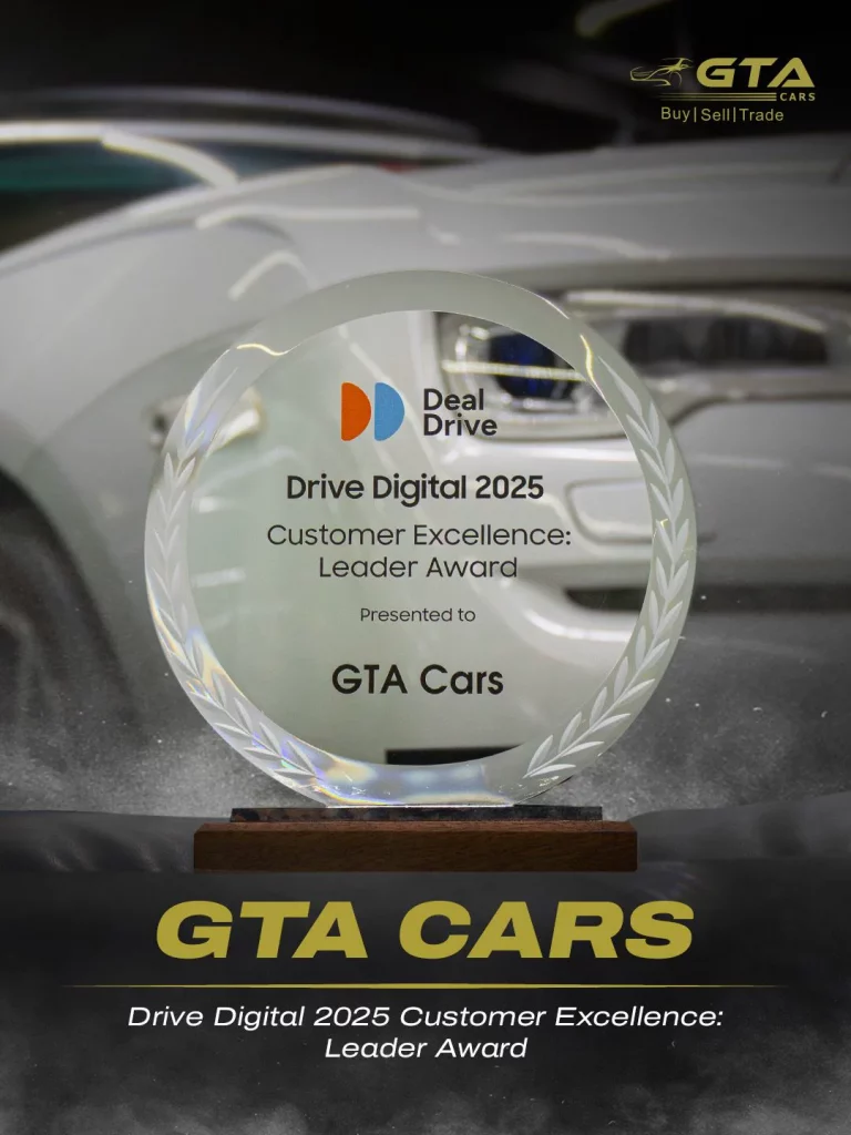 Circular glass Deal Drive trophy engraved “Drive Digital 2025 Customer Excellence: Leader Award, presented to GTA Cars”, standing in front of a white car