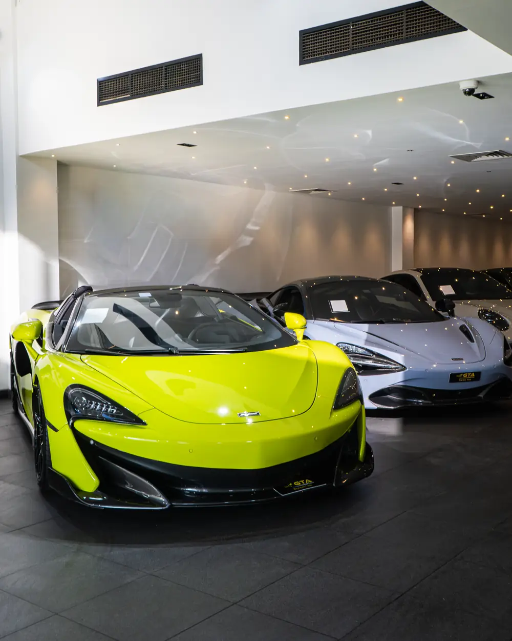 Lime green McLaren 600LT beside a McLaren Artura in the GTA Cars Dubai showroom